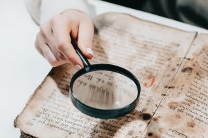 Historian scientist reading antique book with magnifying glass. Translation of religious literature.