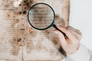 Historian scientist reading antique book with magnifying glass. Translation of religious literature.