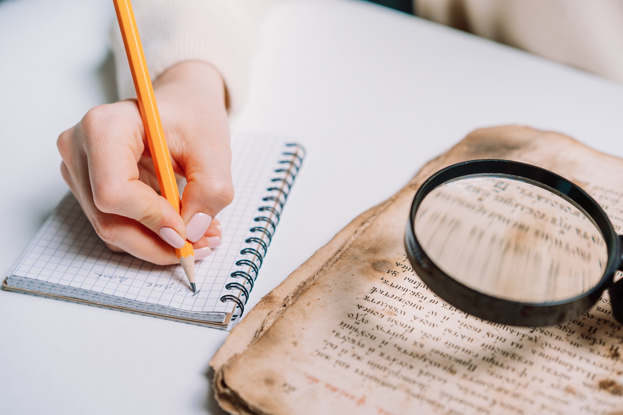 Researcher examines antique book with magnifying glass. Scientific translation of ancient literature